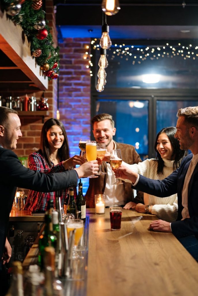 Group of friends in holiday sweaters raising drinks at a Chicago bar