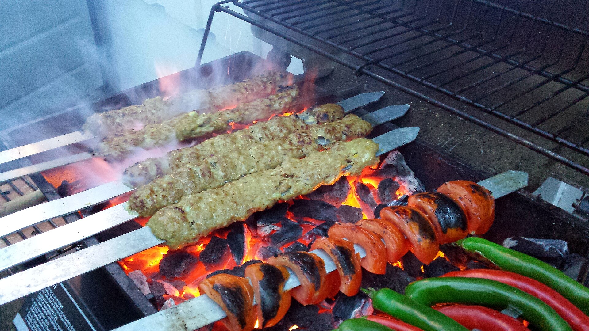 Illustrative photo of koobideh kebab cooking over charcoal, not from Berenjak Chicago
