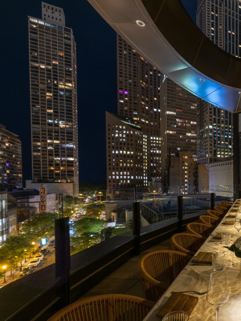 Arla Chicago Gold Coast rooftop terrace dining table with skyline views at night