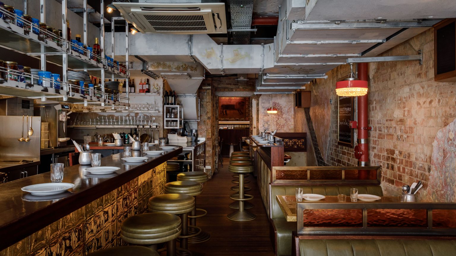 Berenjak restaurant interior with bar, green leather stools, and booth seating