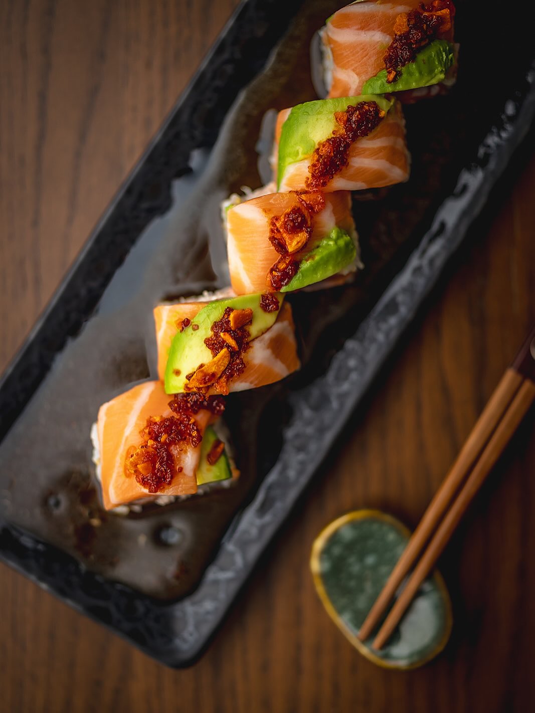 Carlyle Club Chicago salmon avocado roll with chili crunch on a dark ceramic platter