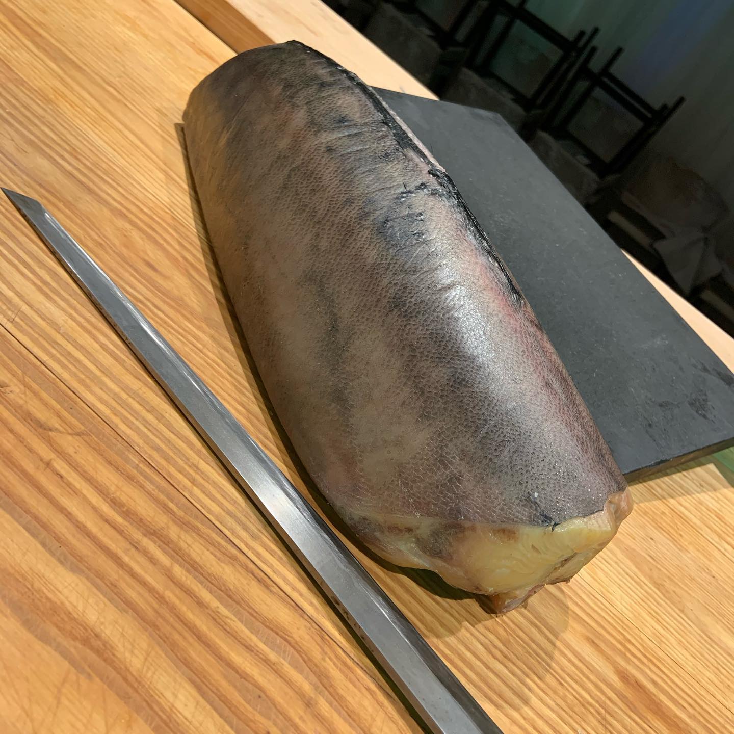 Kyōten Chicago aged buri loin with yanagiba knife on wooden sushi counter