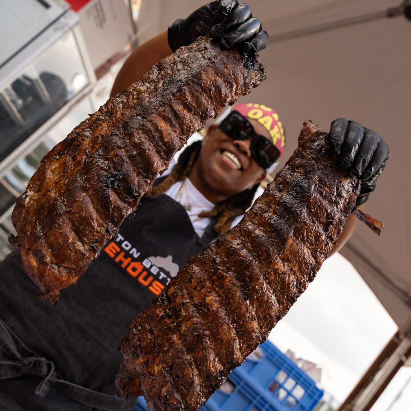 Chef Dominique Leach of Little Betty Smokehouse holding racks of smoked BBQ ribs
