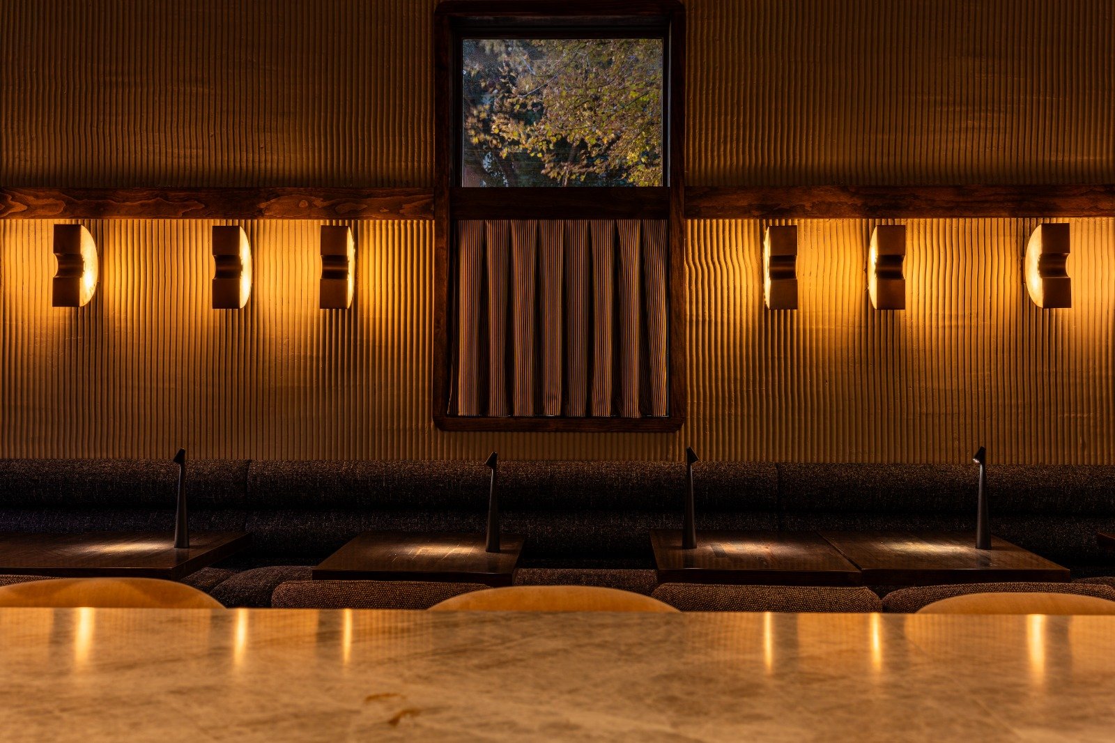 Osteria Gilberto Chicago banquette seating with amber sconces and fluted walls