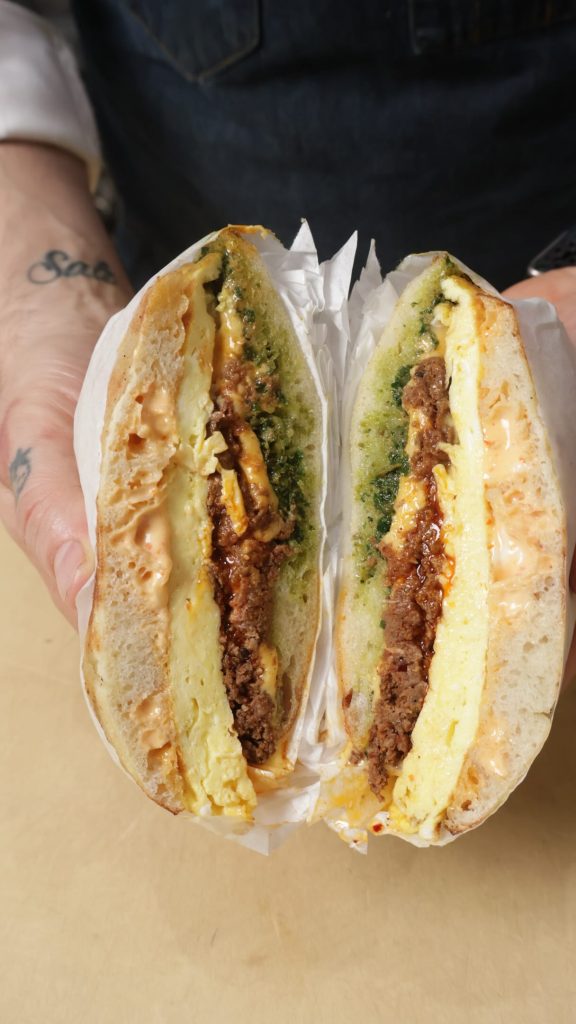 Susu Chicago Wagyu sujuk breakfast sandwich cut in half with eggs and green chermoula