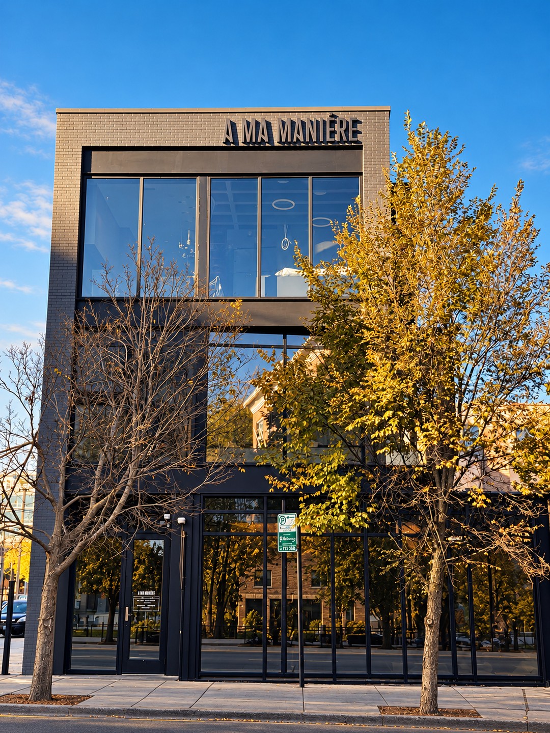 Street view of the A Ma Maniere Chicago storefront with a glass entrance, black lettering above and fall trees on the sidewalk