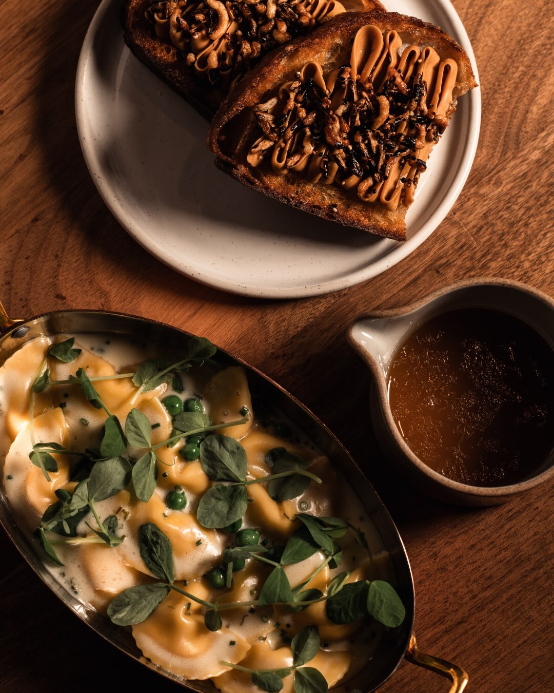 Délice de Bourgogne luna pasta in a copper pot with puffed grain toast and a pitcher of chicken brodo at All Well Chicago