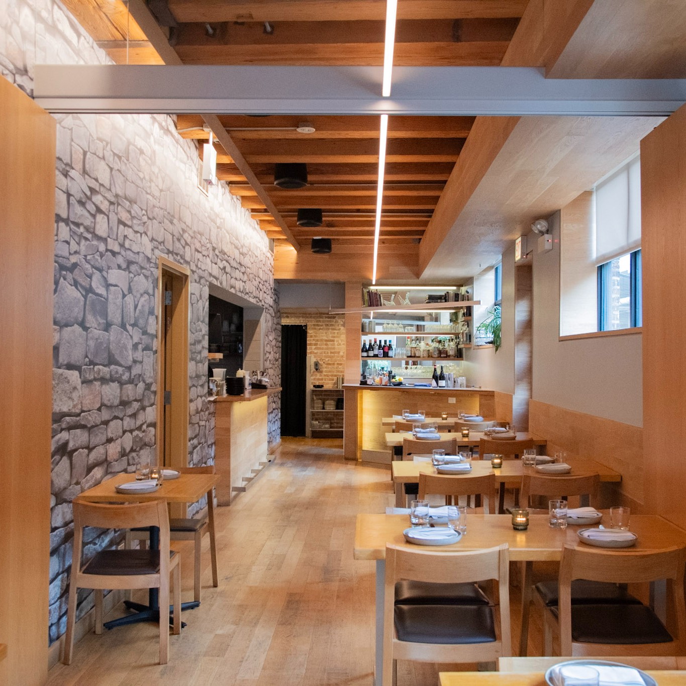 The second-floor dining room at avec West Loop with wood ceiling beams, brick wall and individual tables
