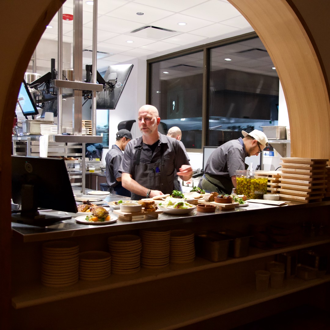 Cooks work the open kitchen pass under an arched opening at avec Highwood during a friends and family dinner