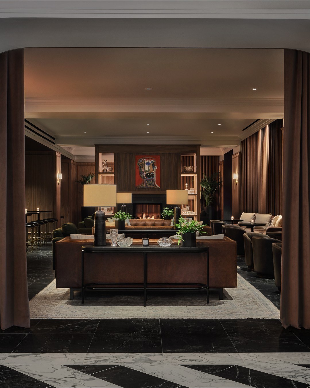 The lounge at Bar Pendry with low sofas, drapery and a fireplace at the far end