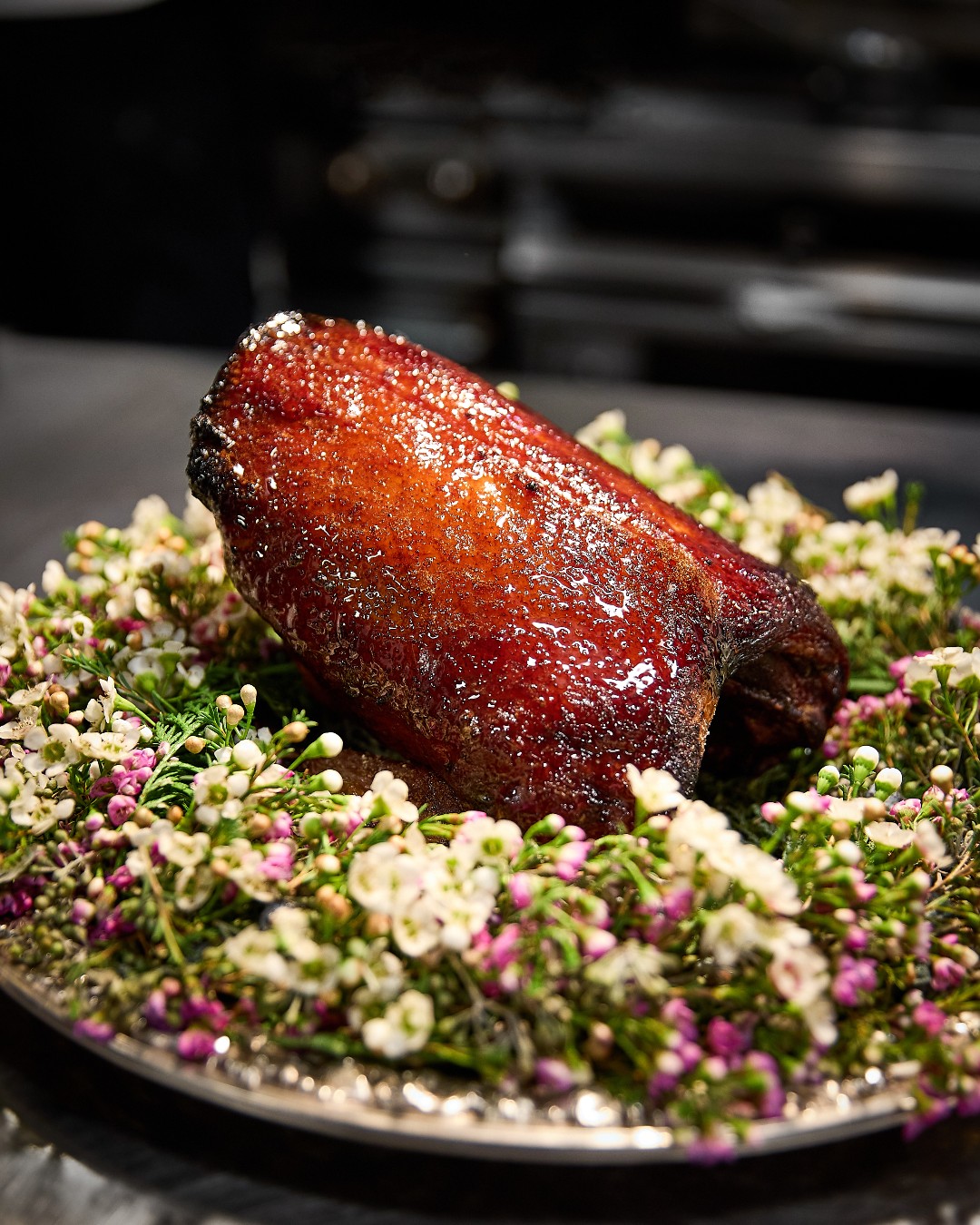 Boka's whole roasted dry-aged duck on a bed of greens and flowers in Chicago