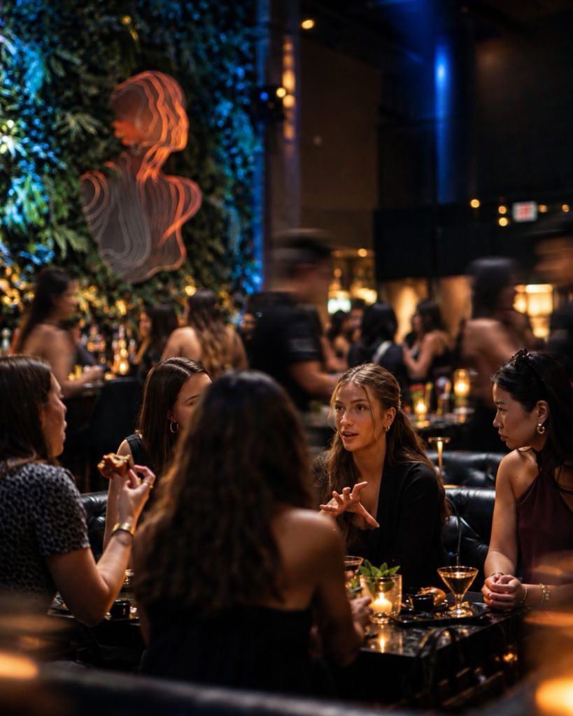 Guests at candlelit tables in the Carbon Chicago lounge beside a living green wall and glowing orange sculpture