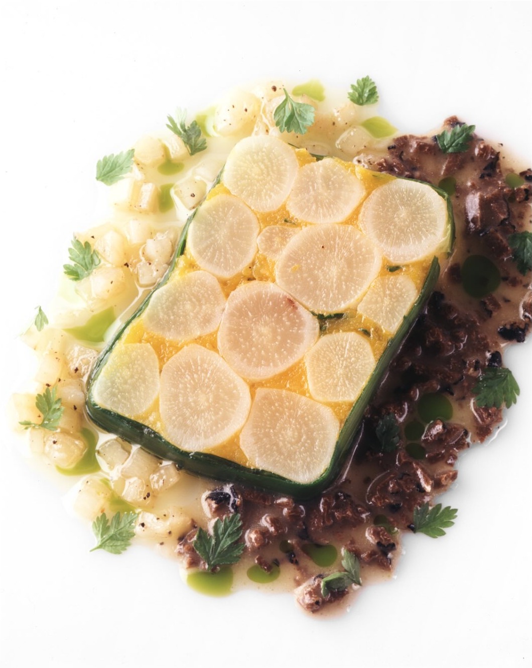 A terrine layered with sweet potato and topped with rounds of salsify, surrounded by diced vegetables, herbs and two vinaigrettes