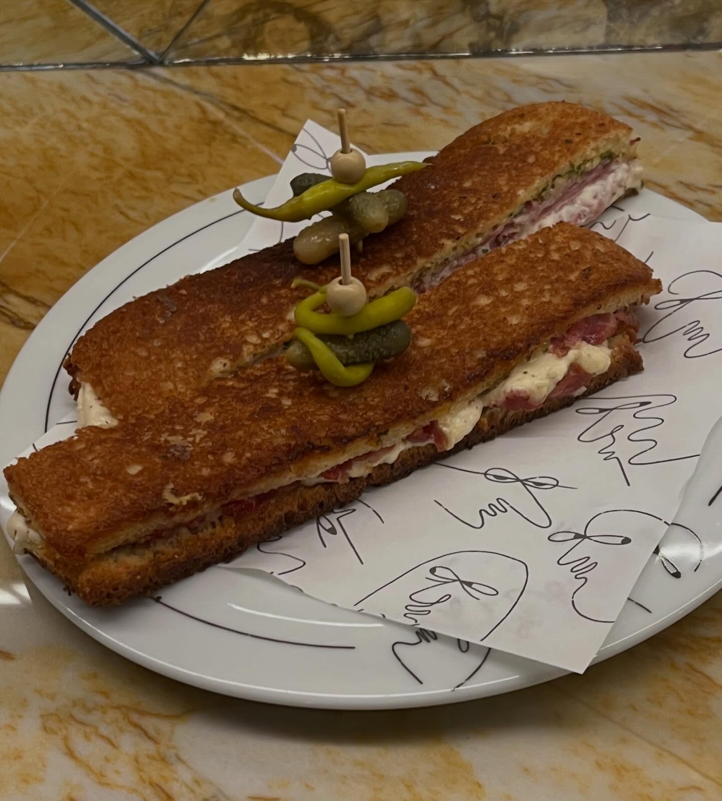 A long, thin croque monsieur with ham and mornay topped with skewered peppers on a Creepies plate
