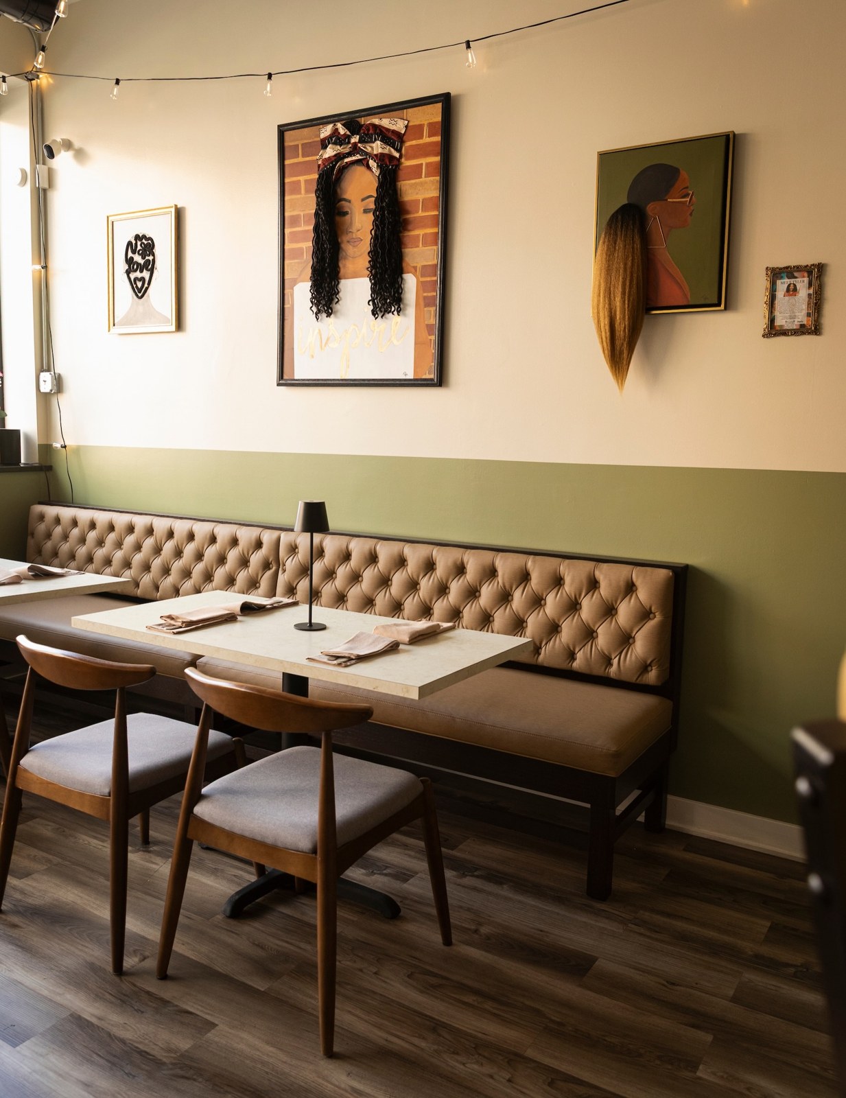 DixiePura Kitchen dining room with a tufted banquette, sage green walls and framed portraits celebrating Black hair