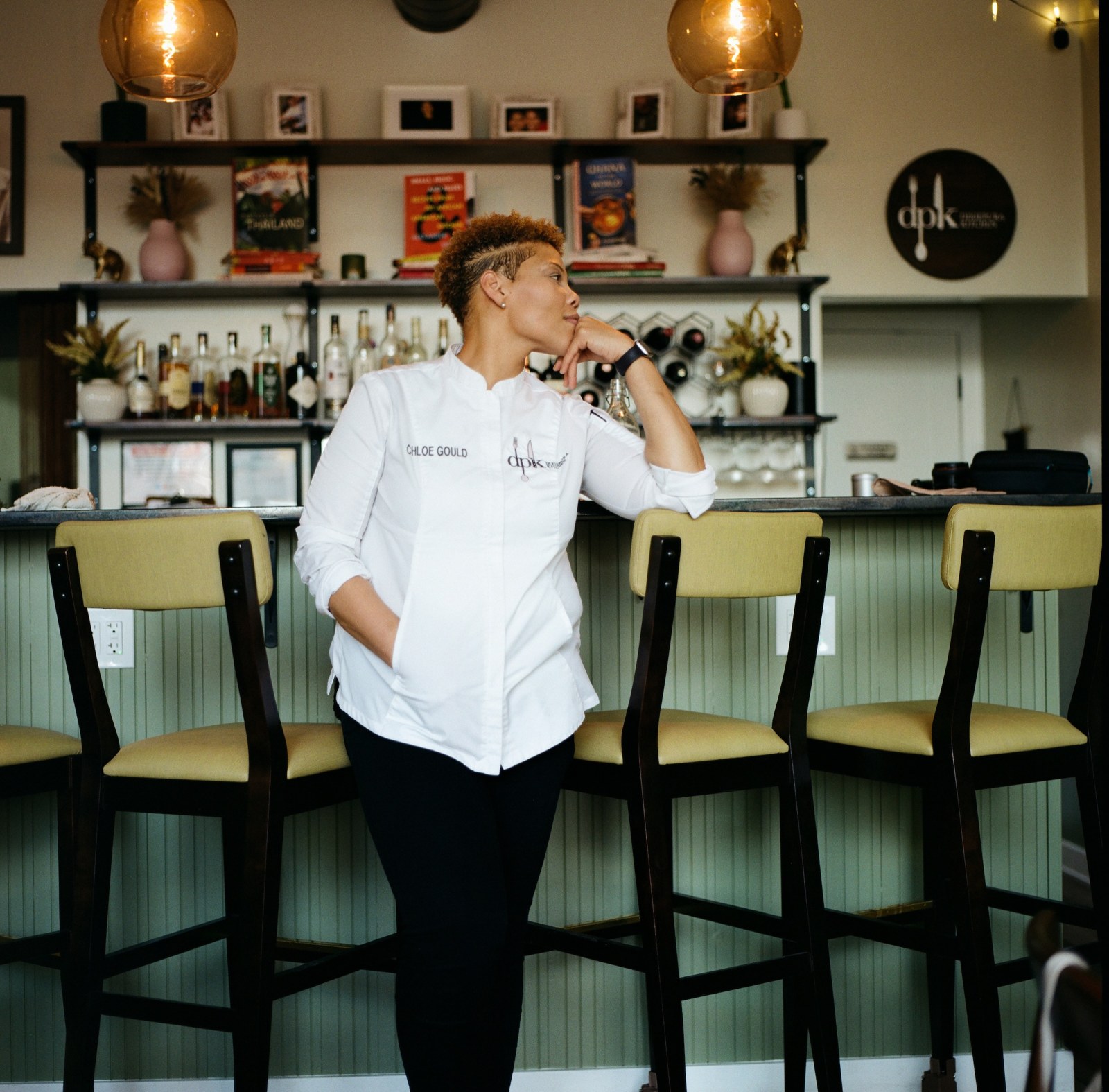 Chef Chloe Gould in a white chef coat standing at the DixiePura Kitchen bar