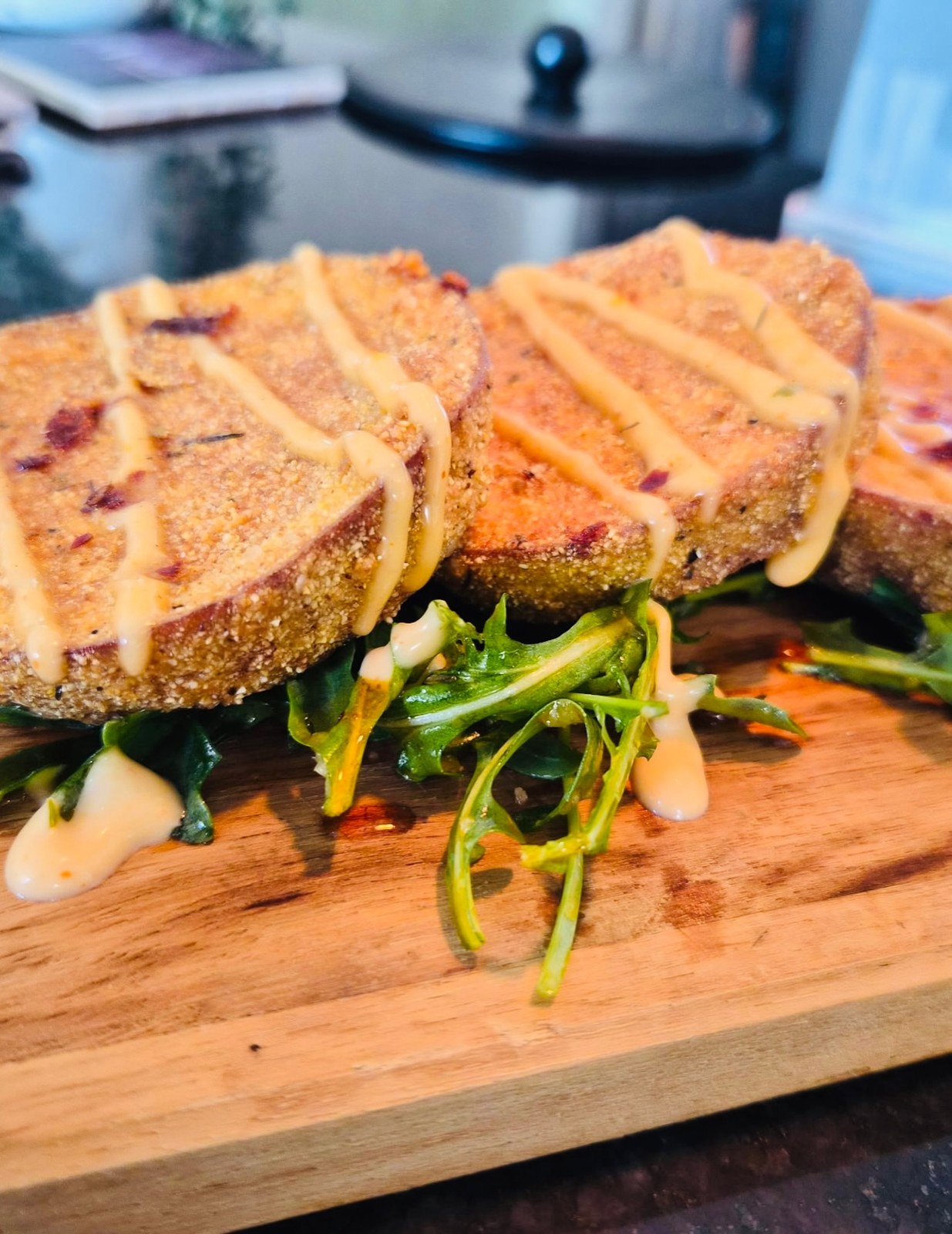 Cornmeal-crusted eggplant slices with remoulade and arugula on a wooden board
