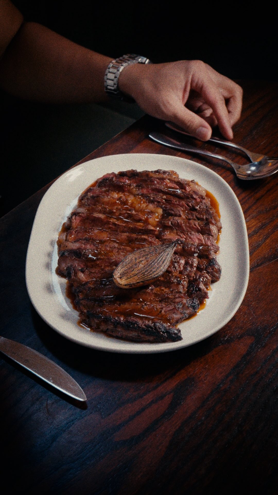 A diner cuts into sliced wagyu ribeye on a white plate at Donia in London