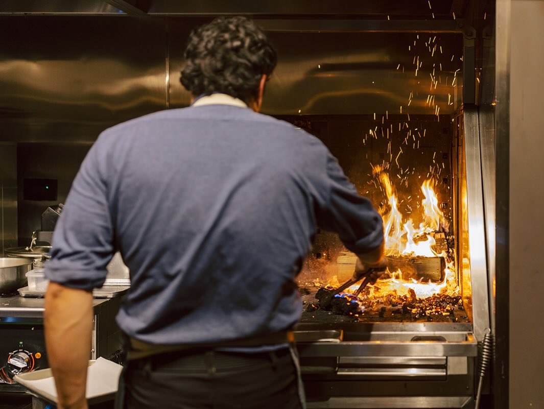 Chef tending the wood-fired hearth at Feld Chicago