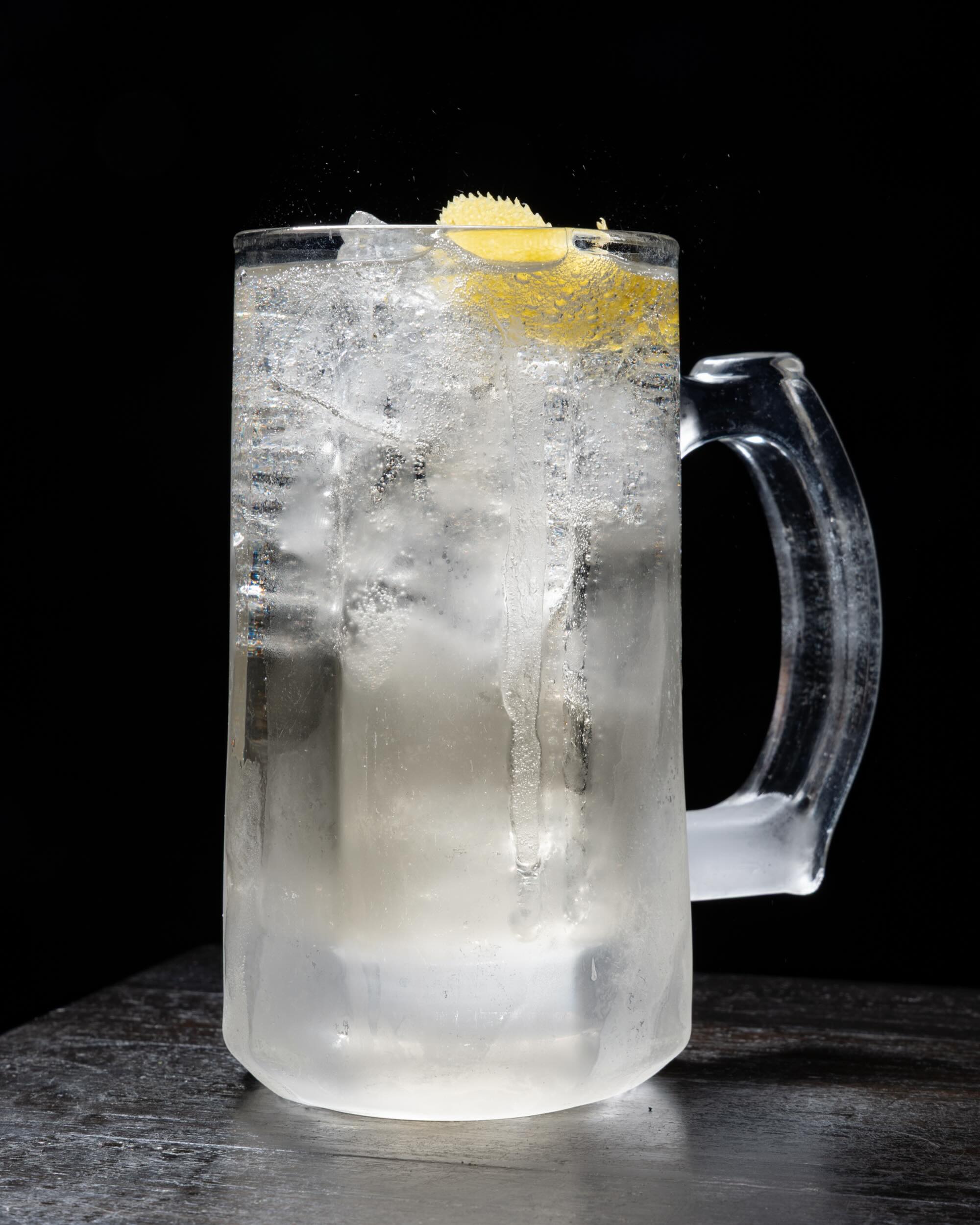 A tall Toki whisky highball with a lemon twist in a frosted glass mug