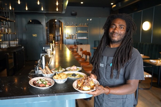 Chef Christian Hunter carrying plates through the dining room at Hooligan Chicago