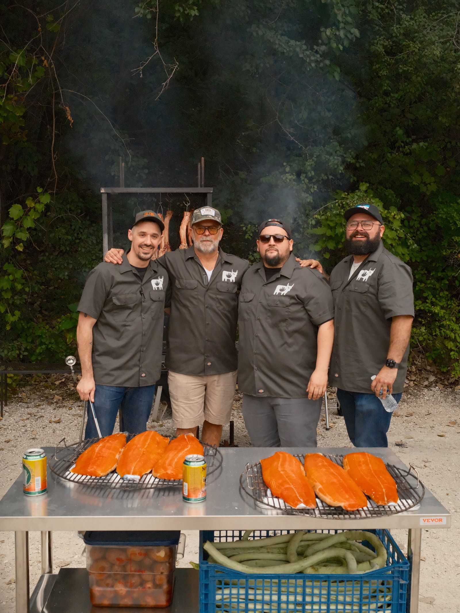 John Manion and three cooks stand behind racks of salmon fillets ready for the smoker outdoors