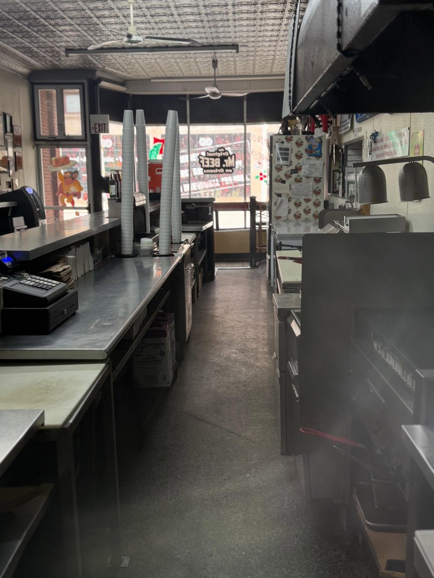 Steam rising off the line behind the long steel counter inside Mr. Beef, with the logo on the front window