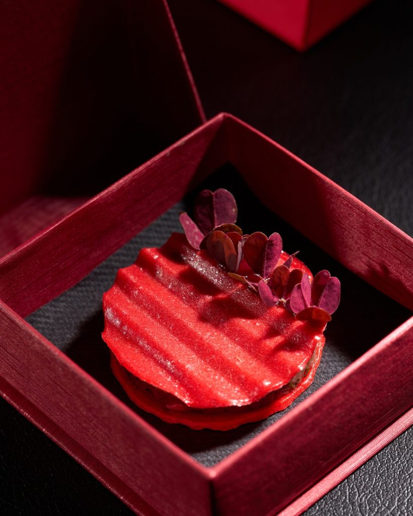 Red pleated opening bite of the Next Fashion menu inside an open red jewelry box
