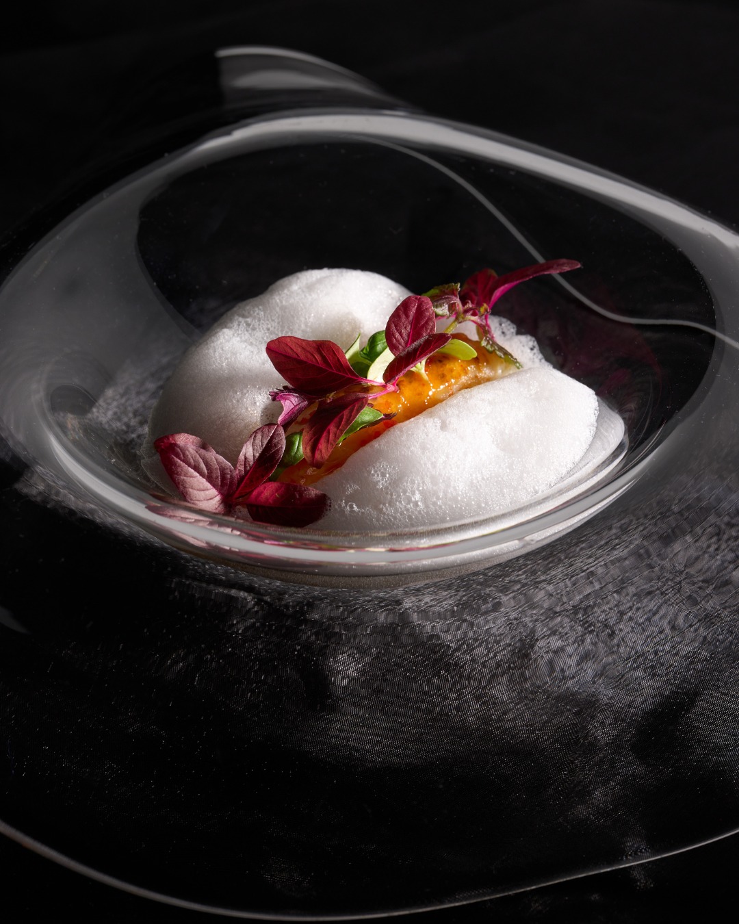 Grilled langoustine under coconut foam with flowers in a glass bowl at Next Chicago