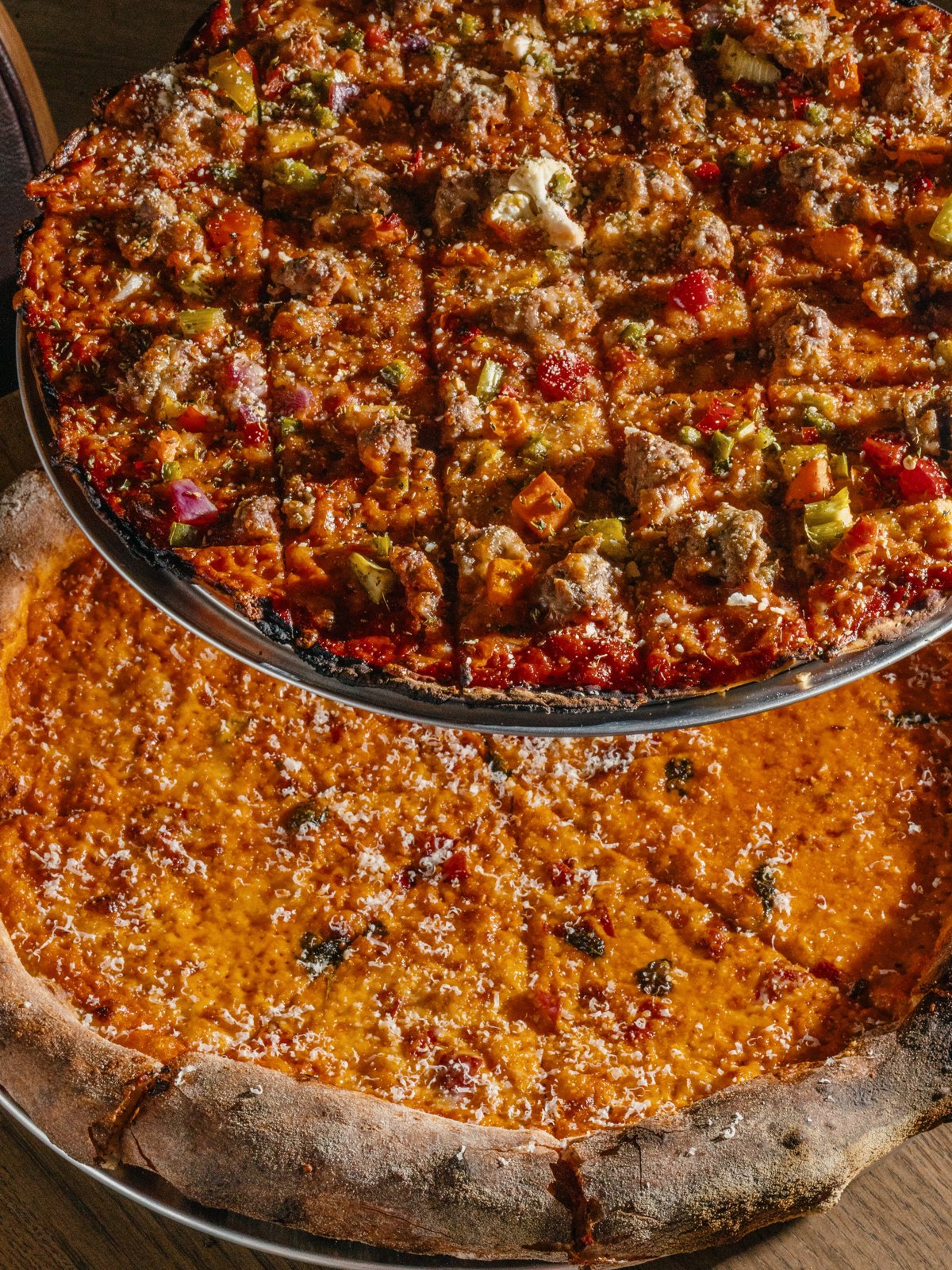 A square-cut Chicago thin crust topped with fennel sausage and giardiniera above a round New York style tomato pie
