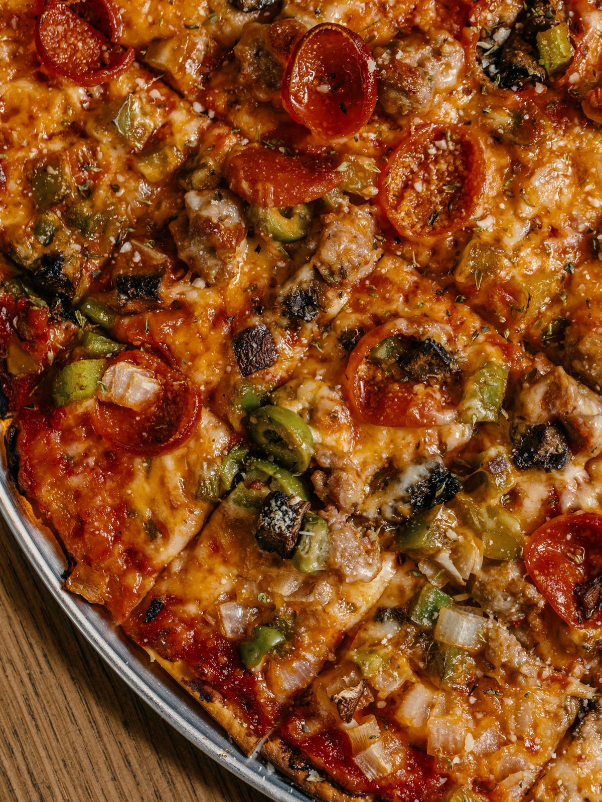 Close view of a Chicago Supreme thin crust pizza cut in squares with pepperoni, sausage, green pepper, onion and olives