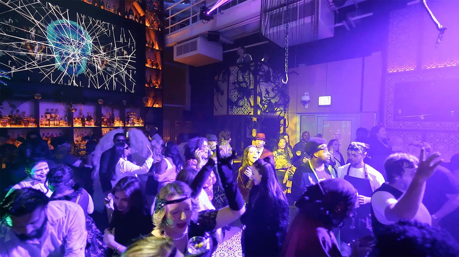 A DJ plays between glowing skeletons under purple light at ROOF on theWit's Halloween party in Chicago