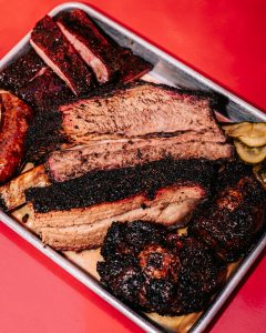 Sanders BBQ Prime cooking language — smoked brisket, ribs, and sausage platter from James Sanders’s kitchen