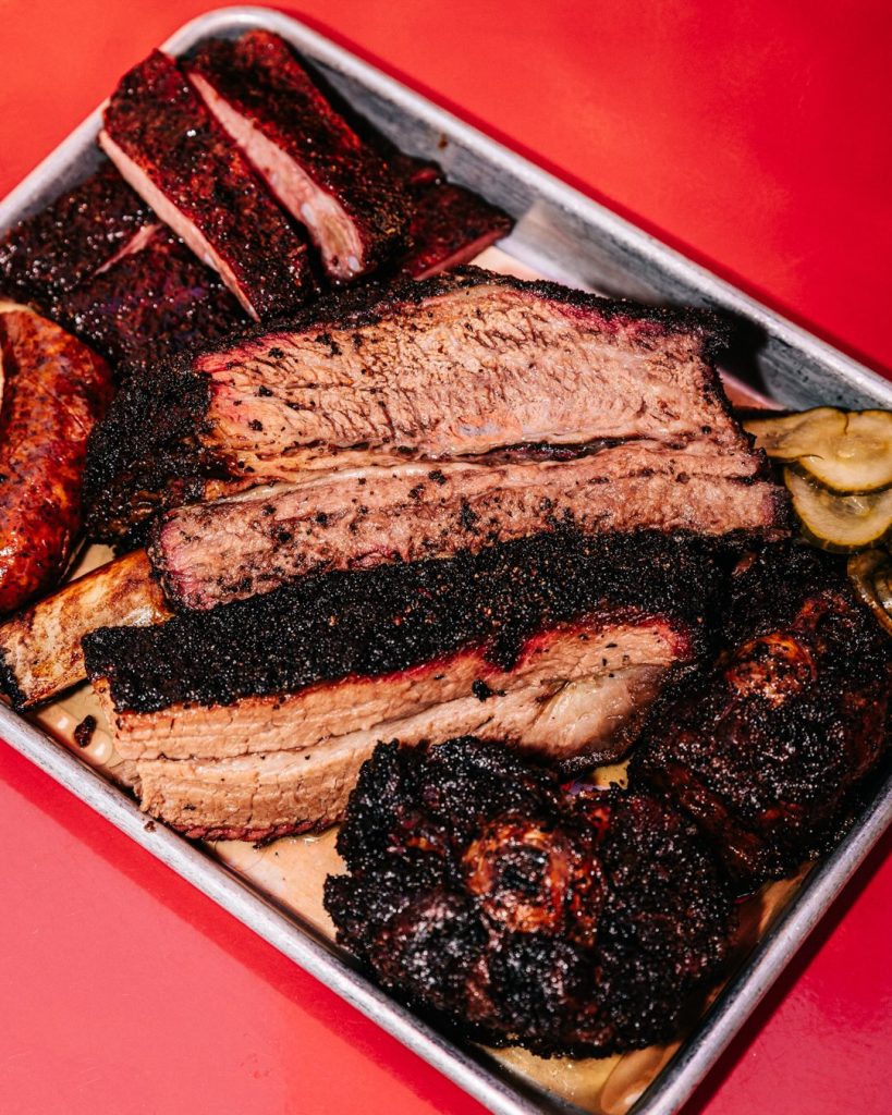 Sanders BBQ Prime cooking language — smoked brisket, ribs, and sausage platter from James Sanders’s kitchen