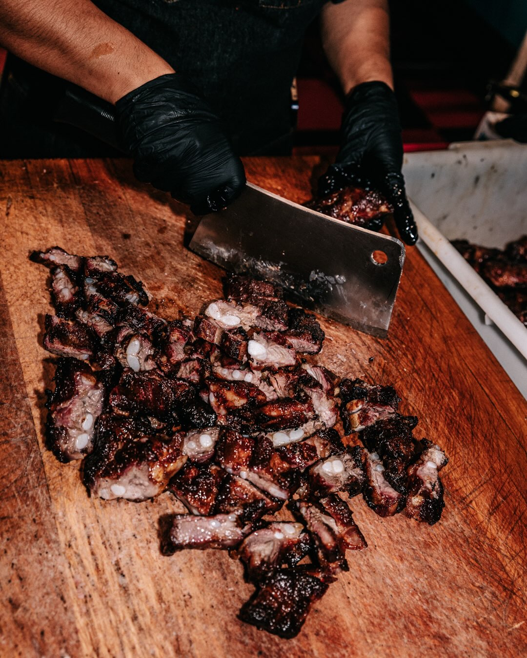 Sanders BBQ Prime chef kitchen — chopping smoked rib tips on the butcher block