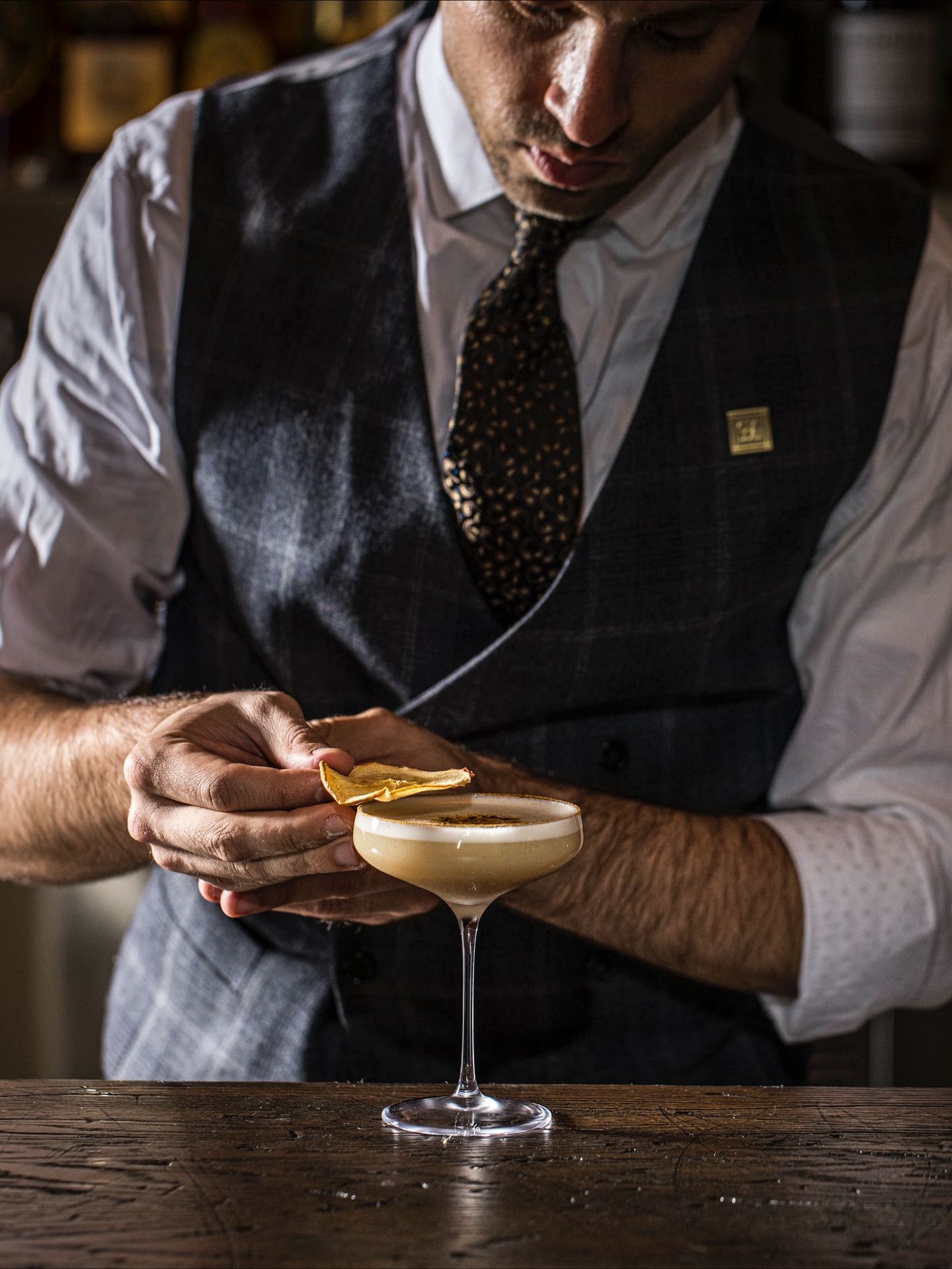 A Sip & Guzzle bartender garnishing a fall apple cocktail in a coupe