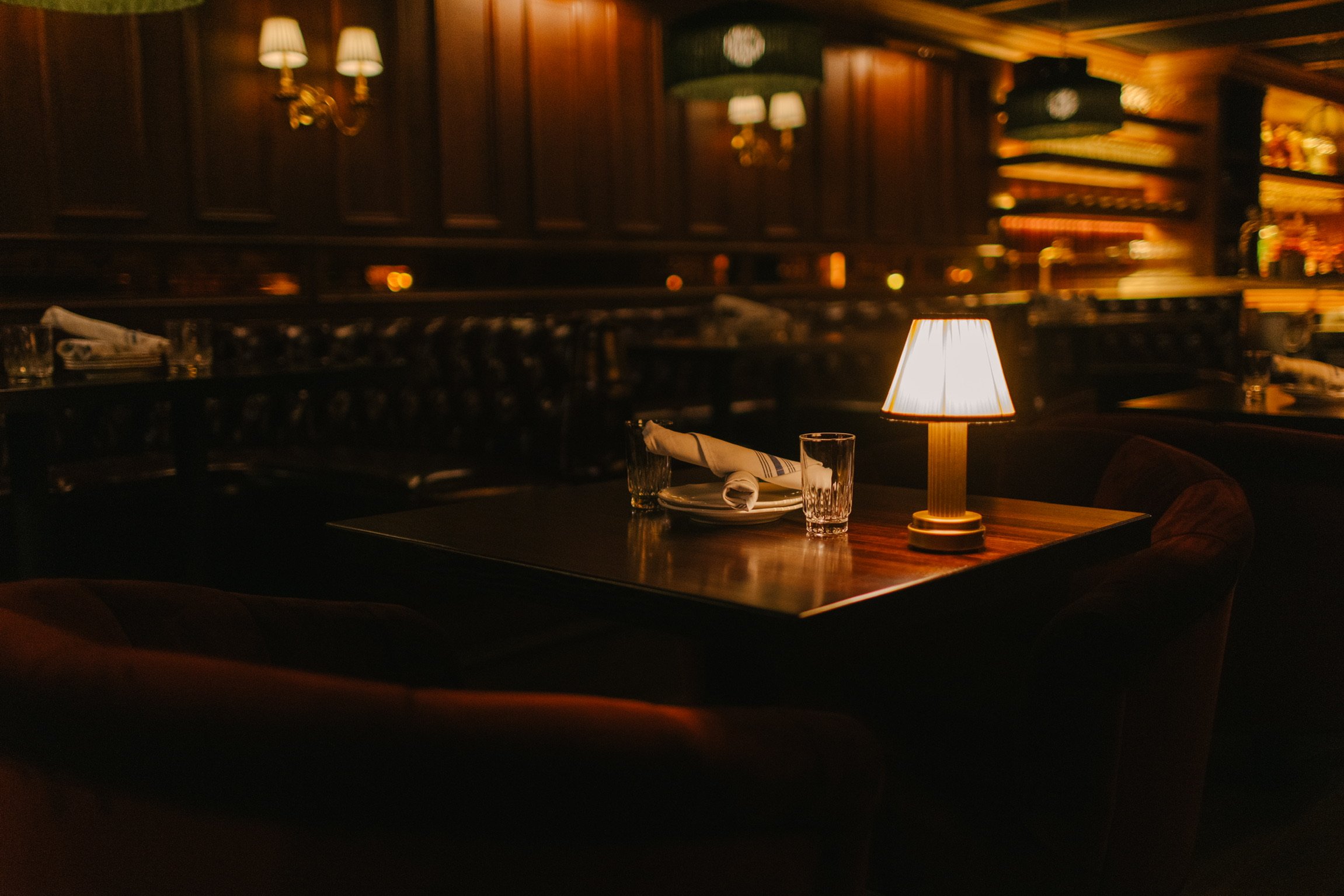 A lamp-lit table and leather booth in the dark wood dining room at The Bull Moose in Lincoln Park