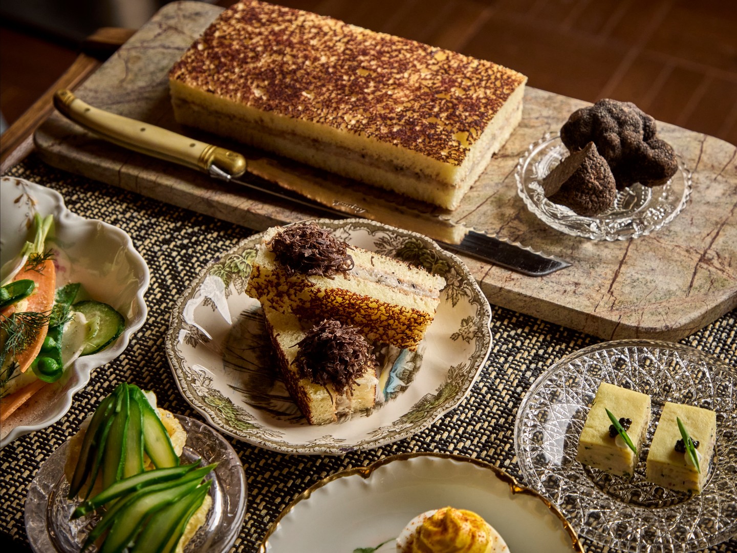 A spread of relish cart bites at The Ives Chicago, with deviled eggs, crudites, terrine slices and a layered torte on vintage glass plates