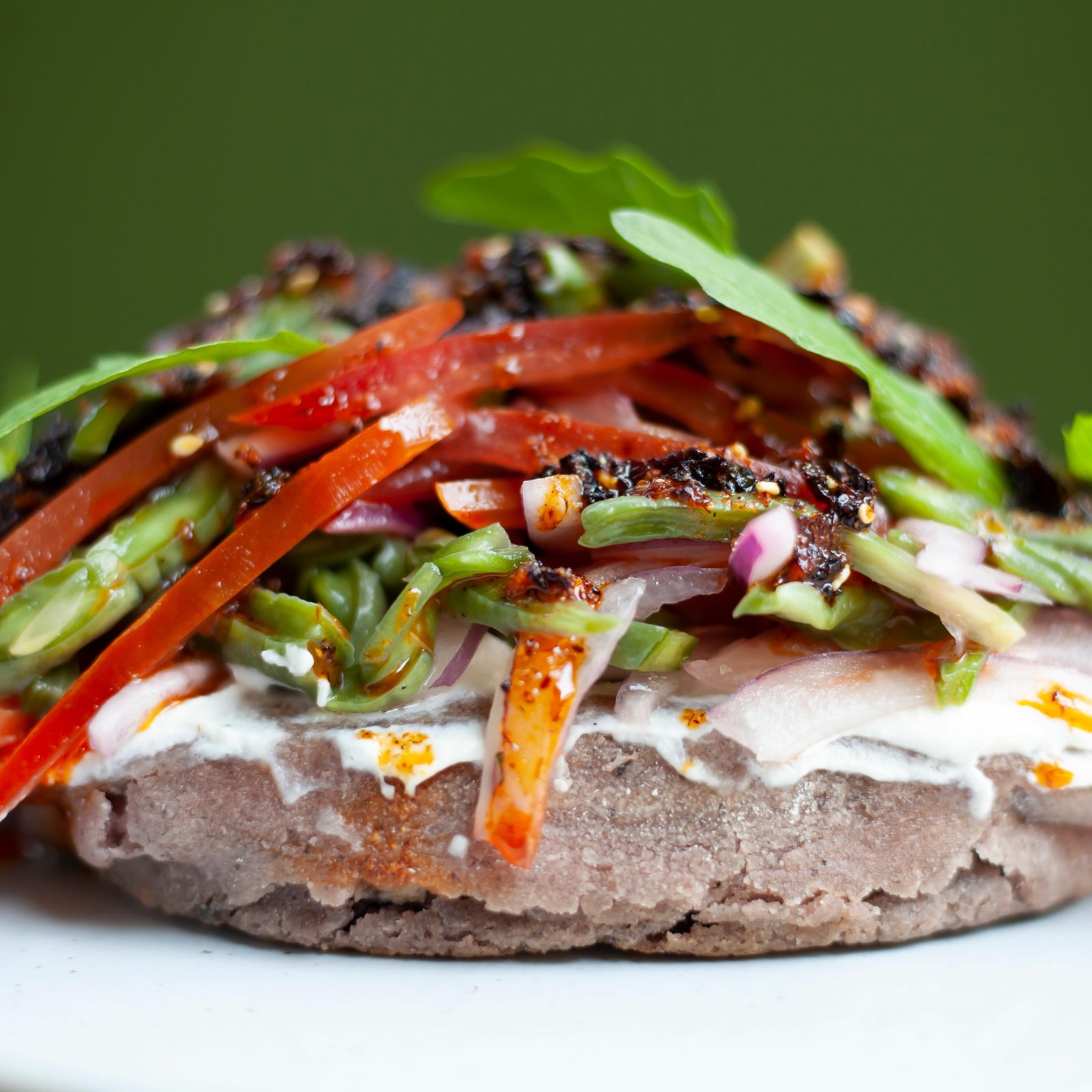 A masa antojito topped with crema, charred peppers and herbs on a white plate