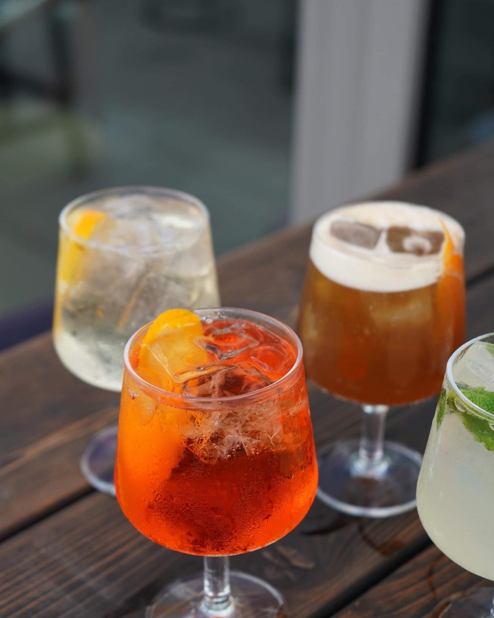 A spritz, a highball and a foam-topped cocktail on a wooden table at The Up Room