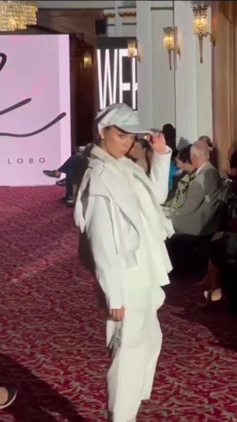 A model in an all-white look walking a runway at a World Fashion Festival show in Chicago